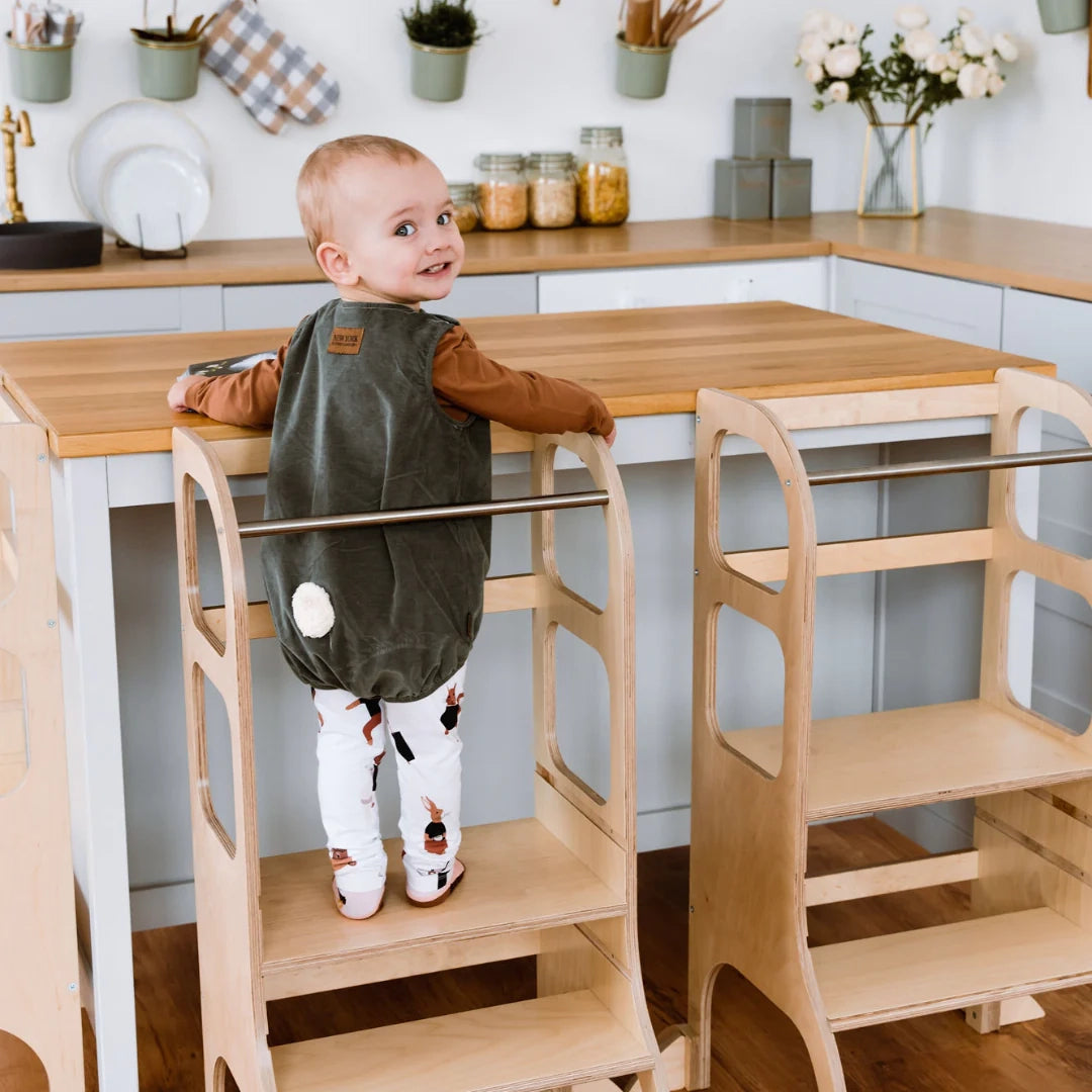 Peuter staat veilig in een houten leertoren aan het keukenblad
